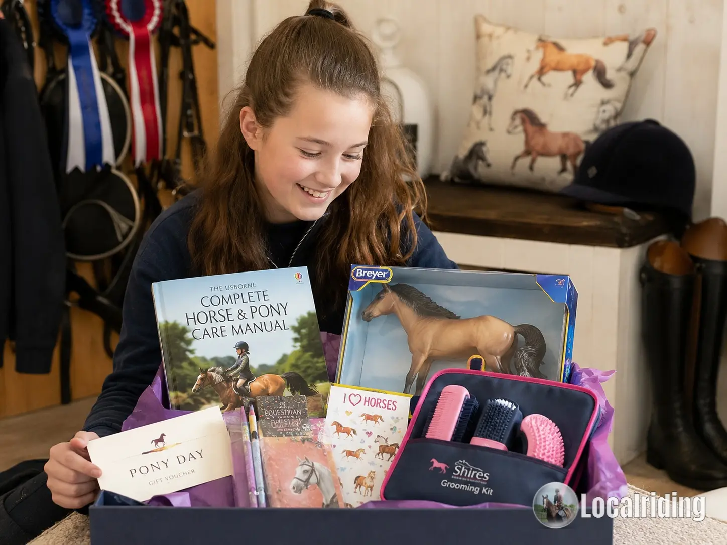 Excited young horse-loving girl opening a gift box containing horse books, a Breyer model horse, pony stickers and a junior Shires grooming kit